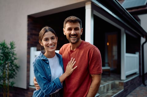 Happy couple standing in front of their new home