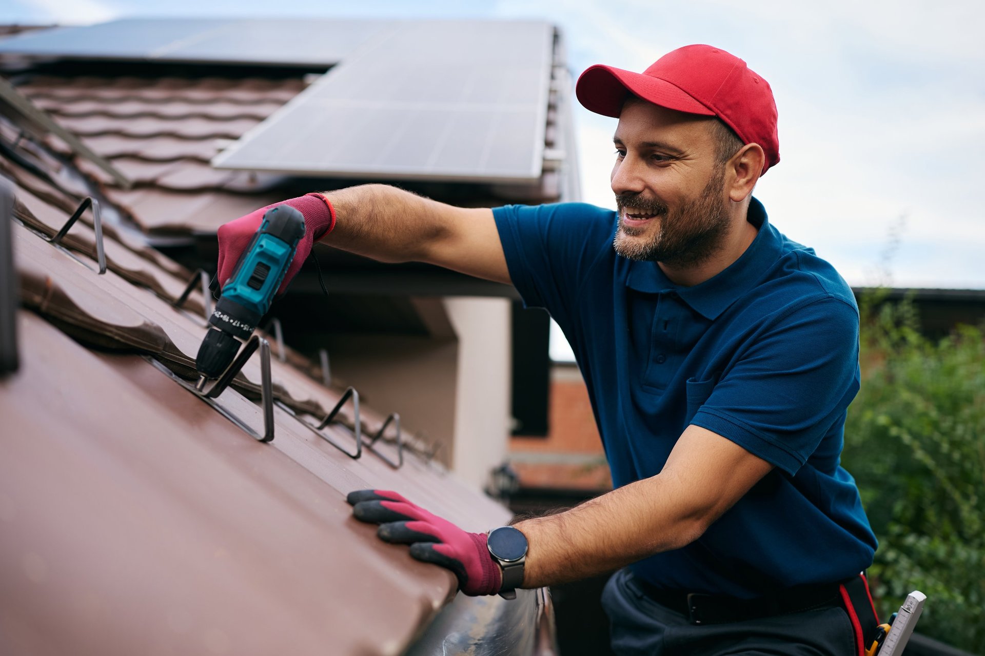 Happy roofer working on the maintenance of the roof of the house